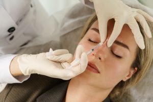 Woman receiving a dermal filler injection in the nose area
